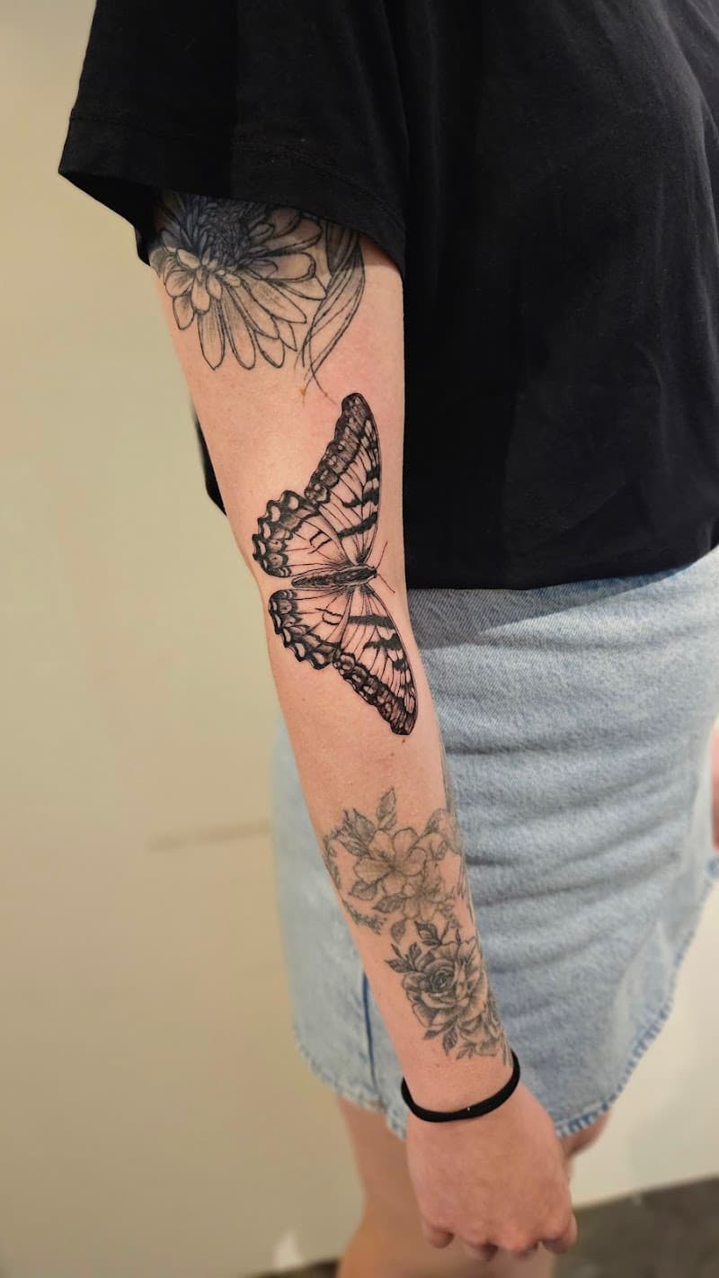 Gedetailleerde zwart-wit vlinder tattoo op de elleboog.