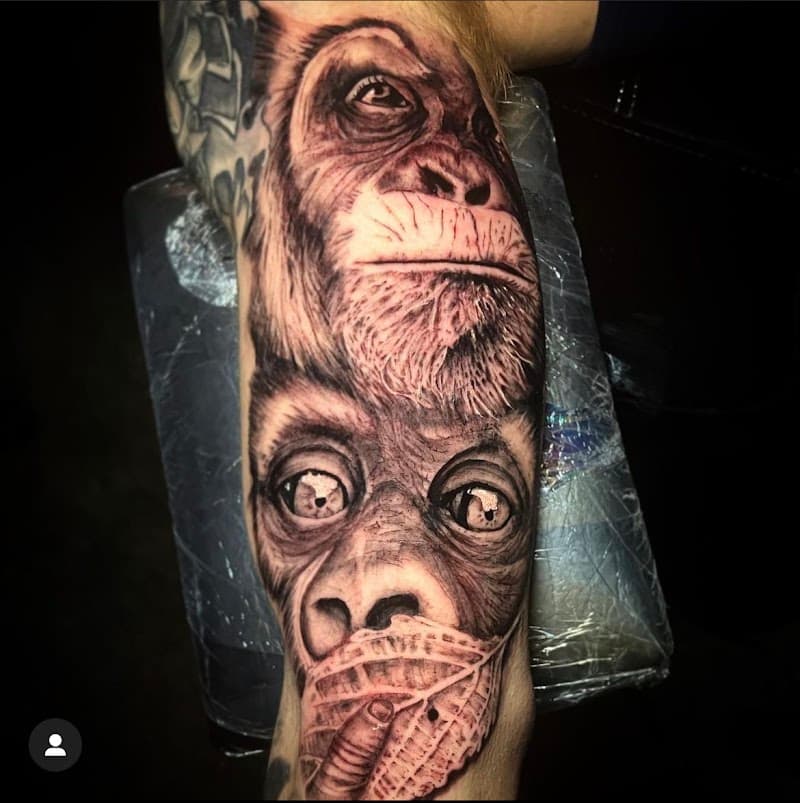 Realistische zwart-wit tattoo van twee chimpansees op een bovenarm.