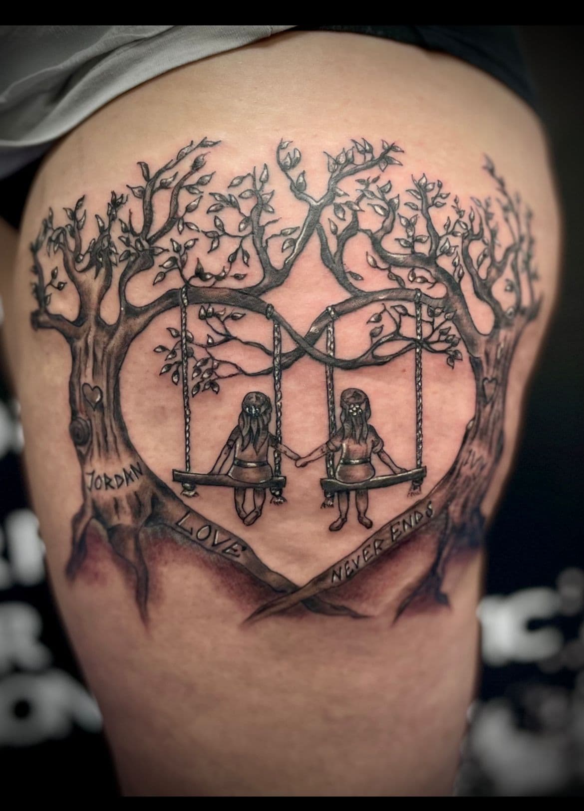 Twee meisjes op schommels in hartvormige bomen met tekst 'Love Never Ends'.