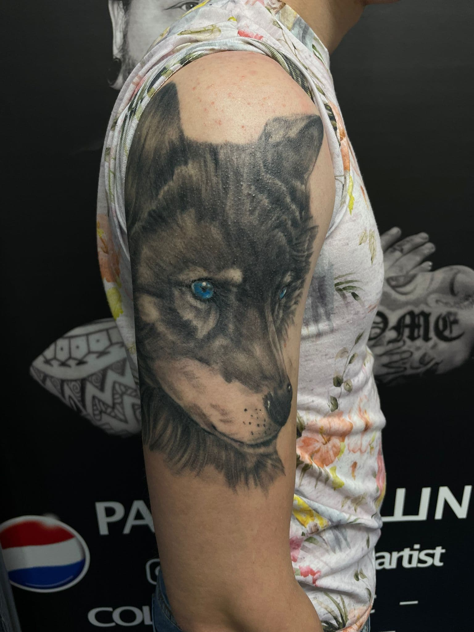 Realistische wolf met blauwe ogen op bovenarm.