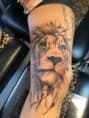 Illustratieve leeuwenkop tattoo op bovenbeen.