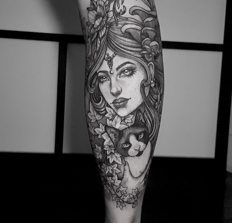 Zwart-wit portret van een vrouw met een kat en bladeren op het onderbeen.