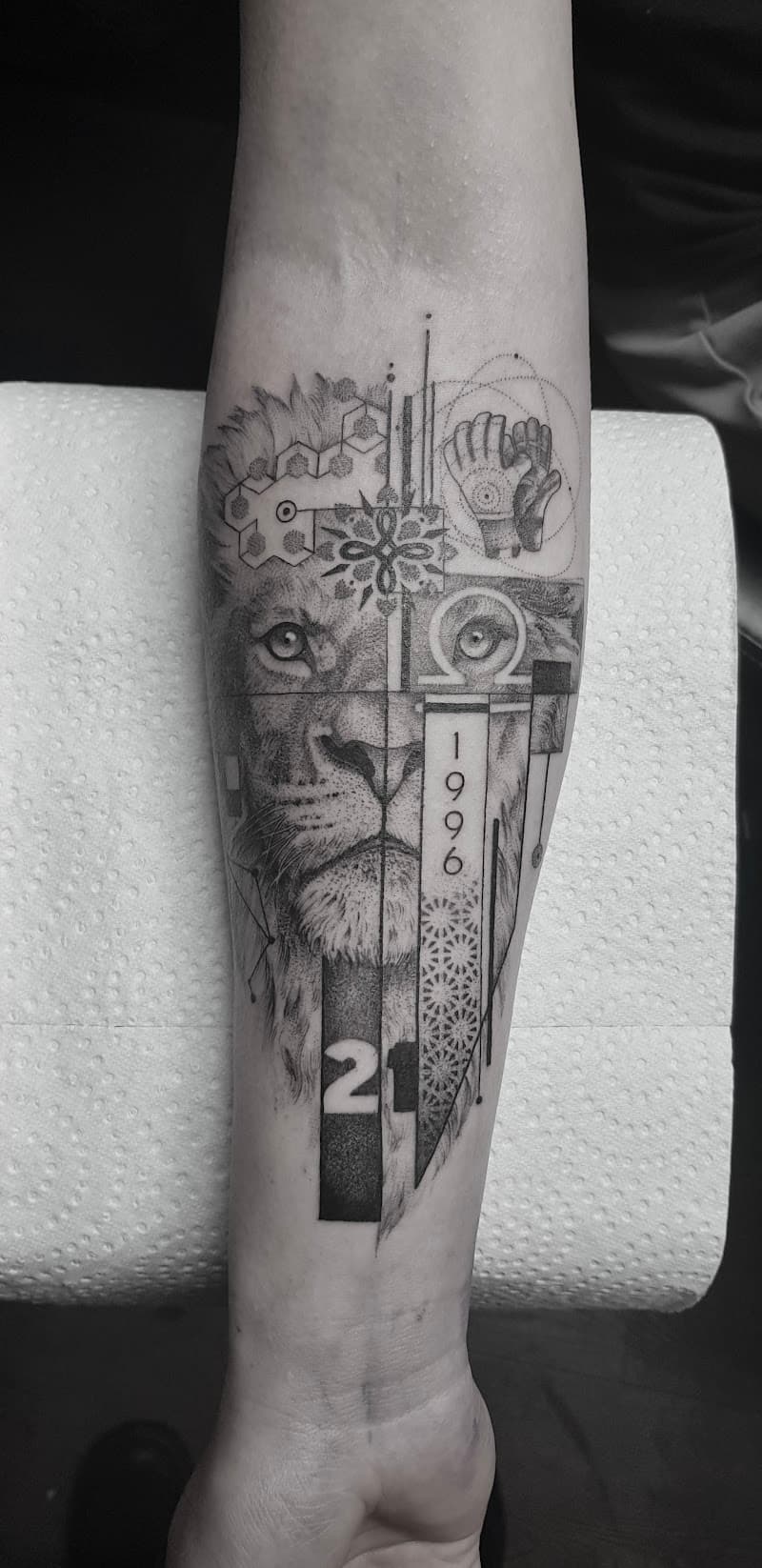 Geometrische leeuw met jaartal 1996 en nummer 21 op onderarm.