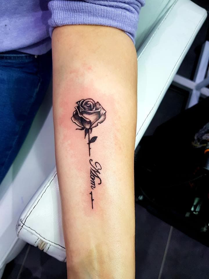 Zwart-wit roos met 'Mom' tekst op onderarm.