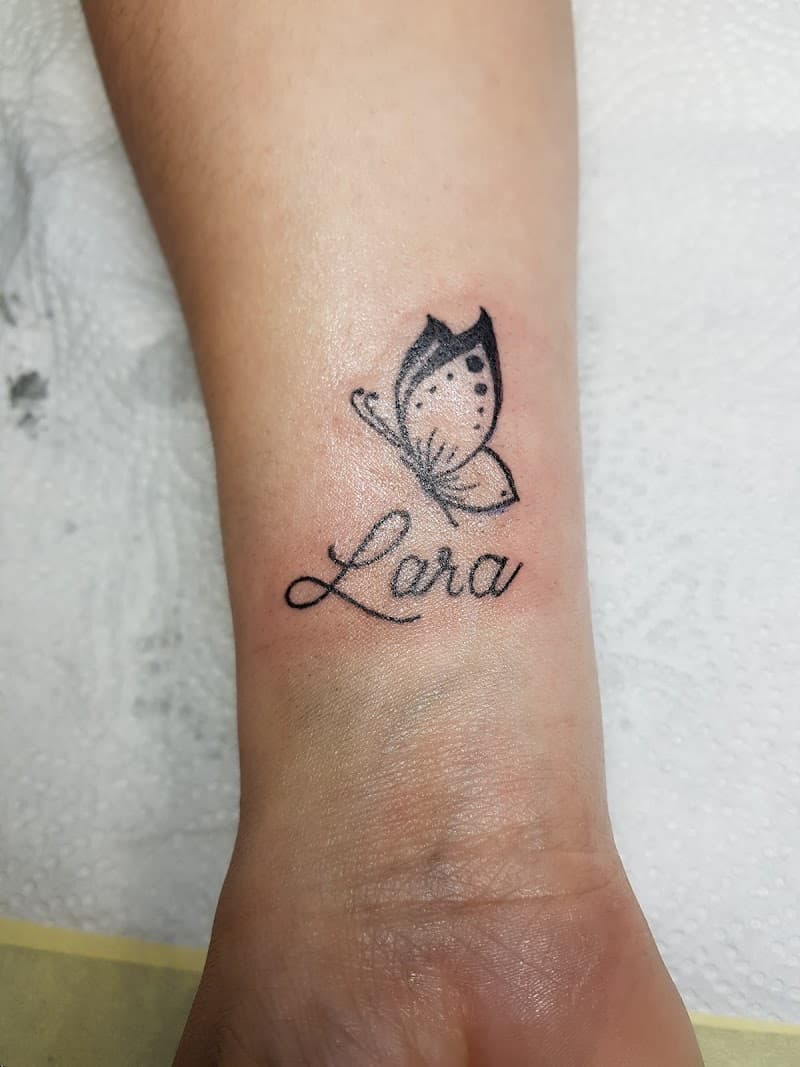 Kleine vlinder met de naam 'Lara' in sierlijk schrift op de pols.