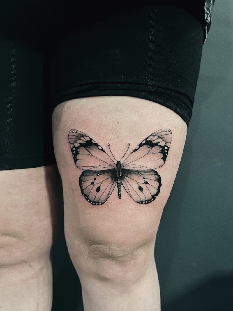 Zwart-wit vlinder tattoo op het bovenbeen.