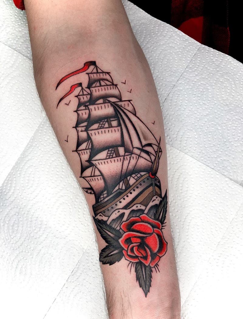 Traditioneel zeilschip met rode roos op onderarm