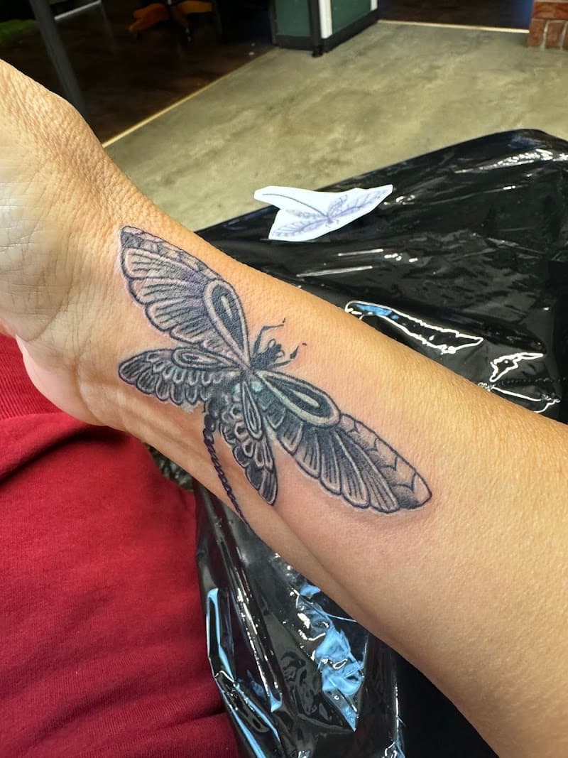 Zwart-grijze libelle tattoo op de pols.