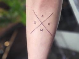 Minimalistische 'GAME' letters in een kruis op de onderarm.