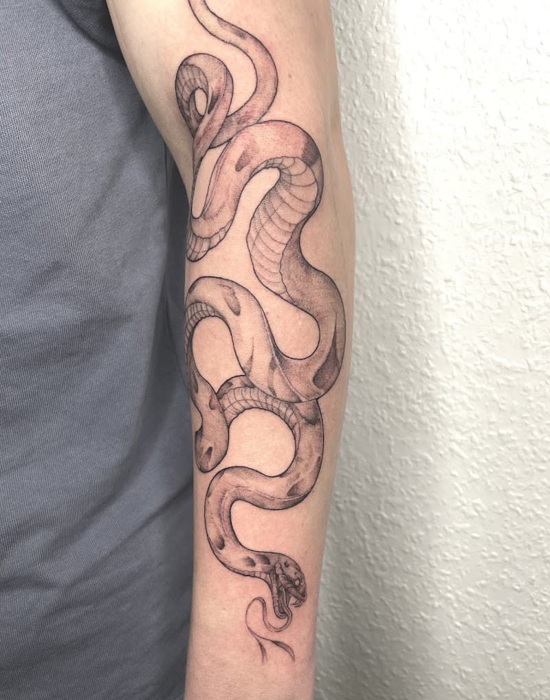 Gedetailleerde slangentattoo in zwart-wit op de onderarm.
