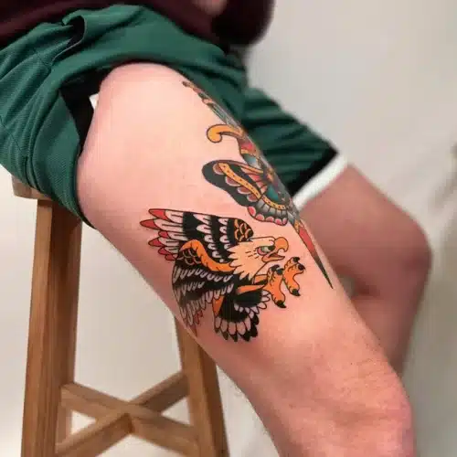 Traditionele adelaar en vlinder op bovenbeen.