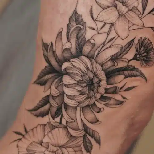 Blackwork bloemen tattoo met chrysant en narcis op de voet.