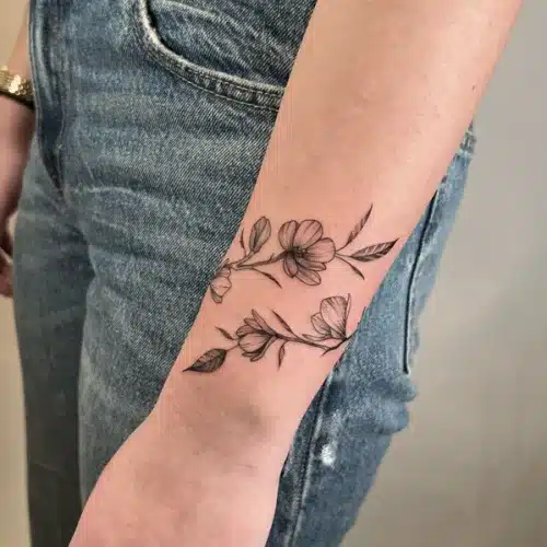 Elegante fineline bloementak tattoo op de pols en onderarm.