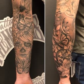 Zwart-wit sleeve met La Catrina, vlinders en klok op onderarm.
