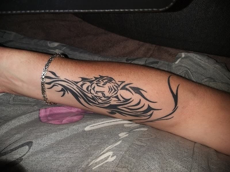 Tribal tijgerkop tattoo op onderarm.