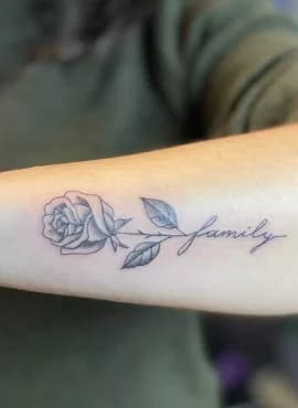 Fineline roos met 'family' tekst als steel op onderarm.