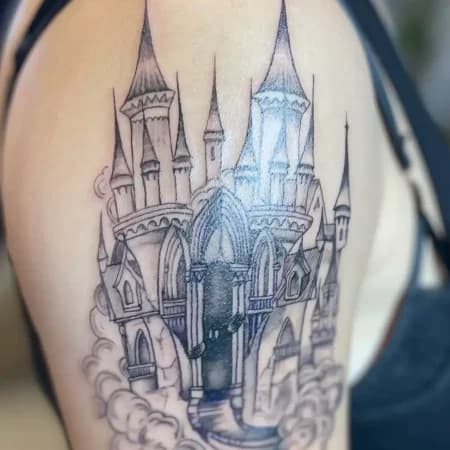 Zwart-wit illustratieve tattoo van een kasteel op de bovenarm.