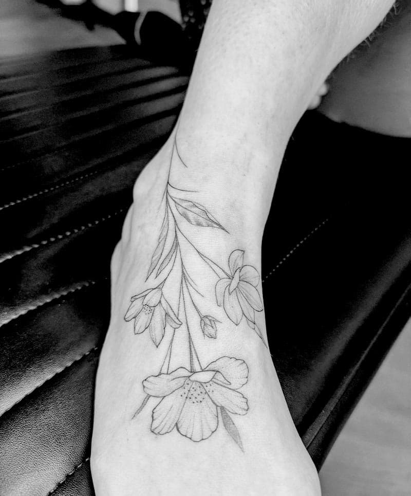 Fineline bloemen tattoo op voet en enkel.