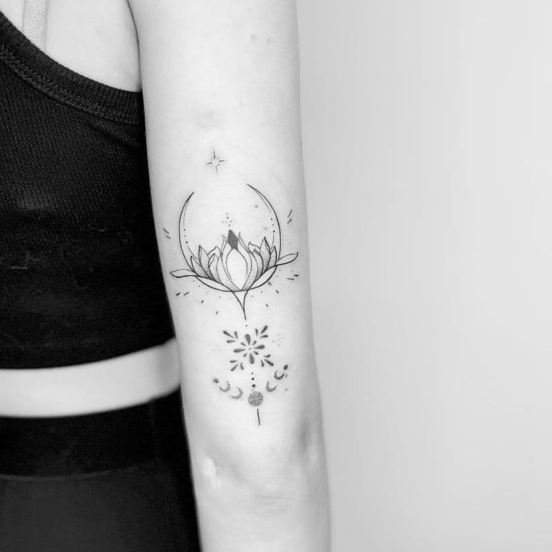 Fineline lotus met maan en ornamenten op bovenarm.