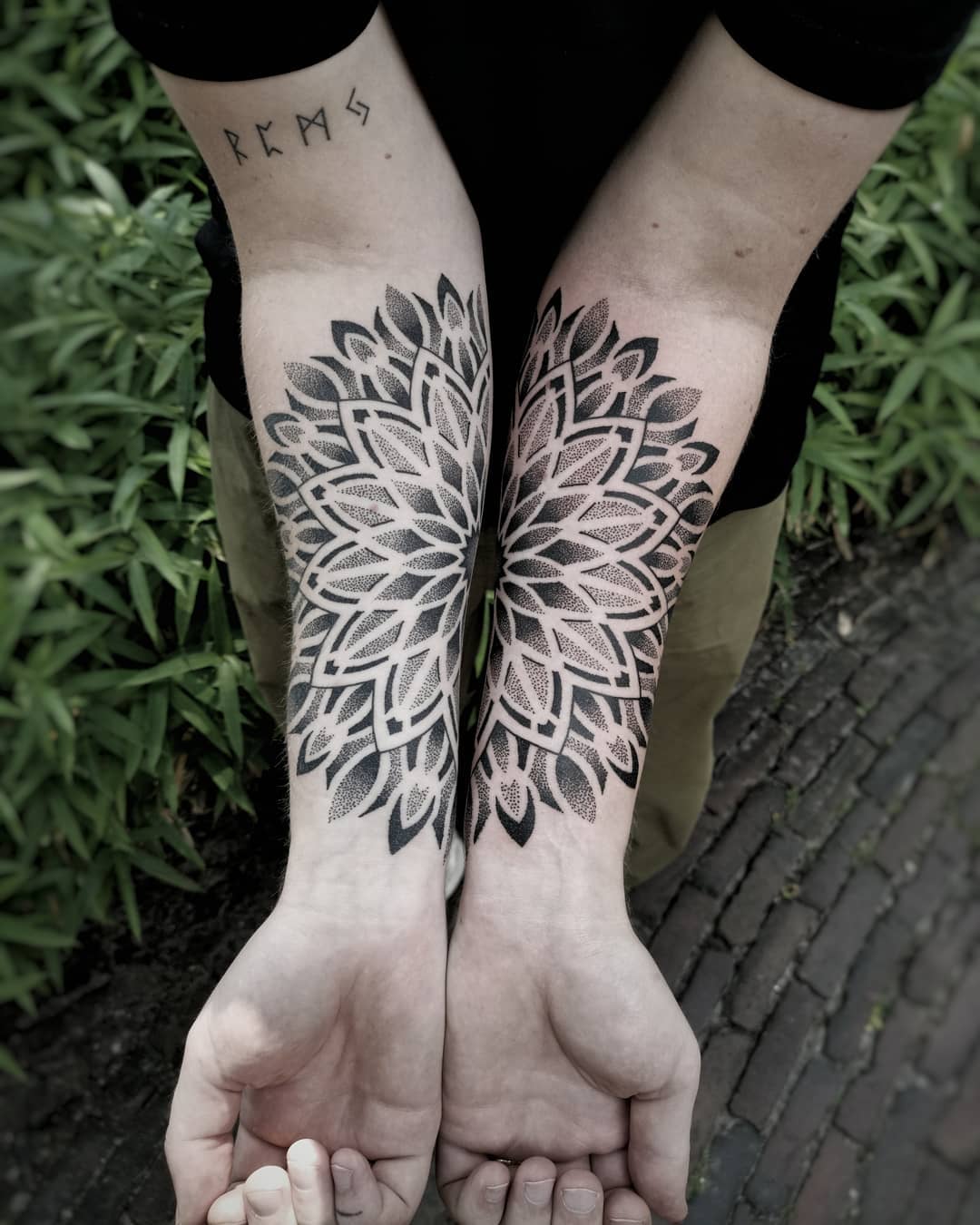 Twee grote dotwork mandala tattoos op beide onderarmen.