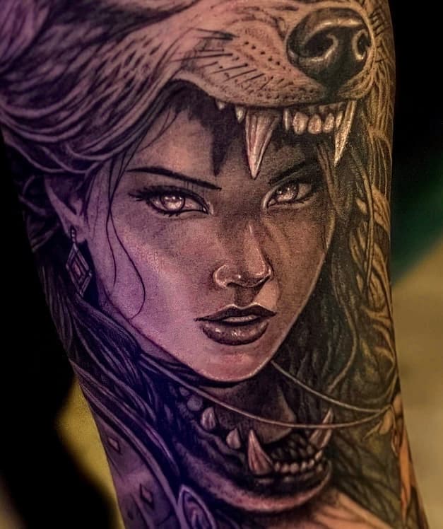 Realistische tattoo van een vrouw met een wolvenhoofdtooi.