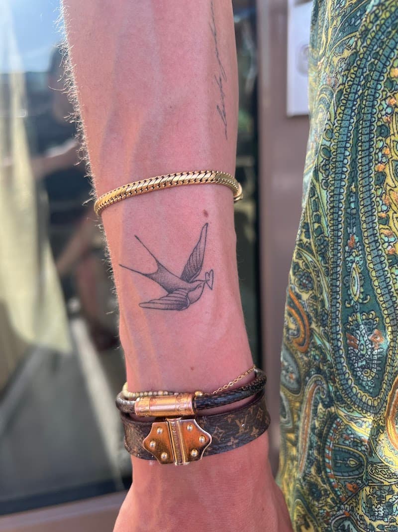 Fineline zwaluw tattoo op de pols.