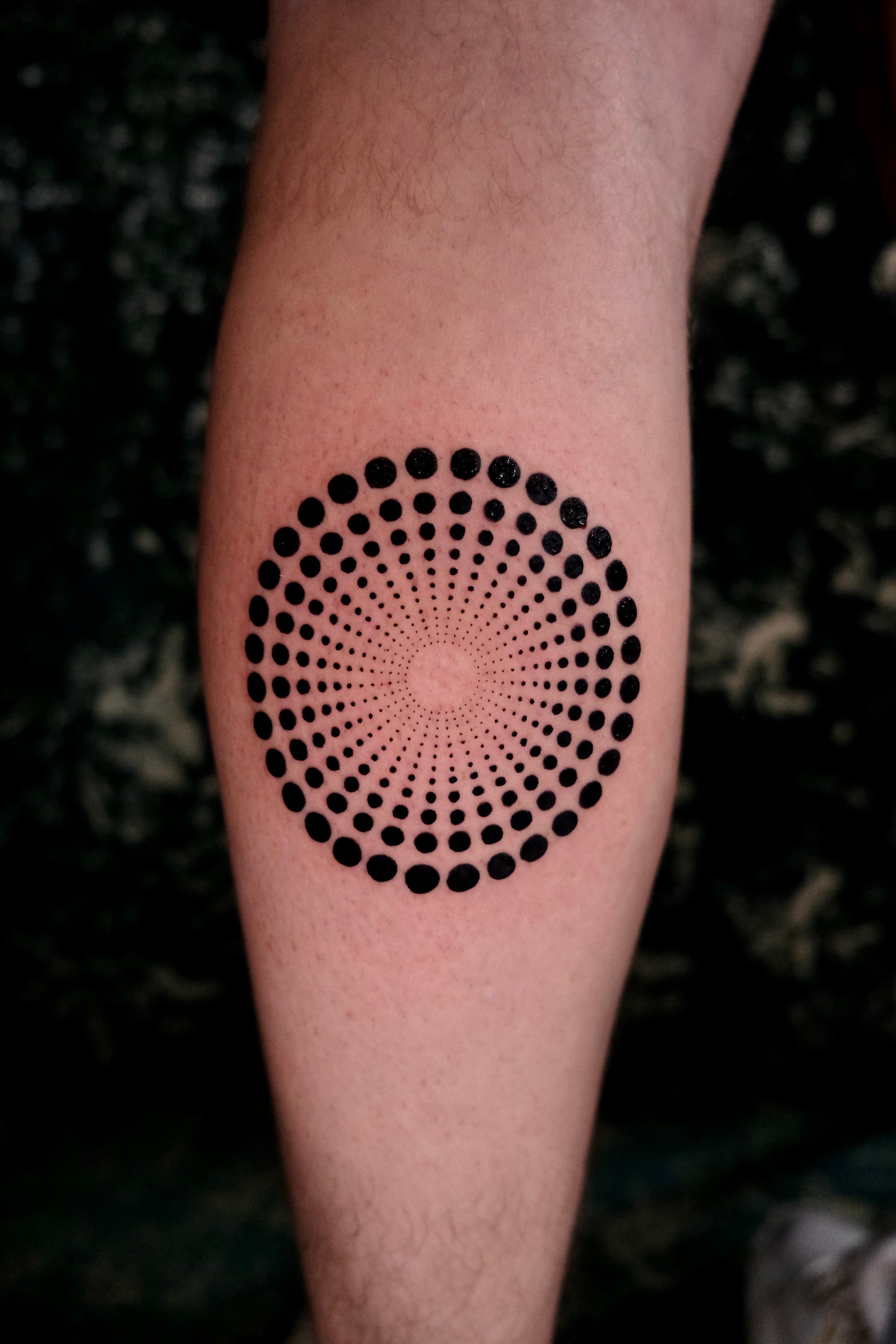 Cirkelvormig patroon van zwarte stippen met optische diepte op onderbeen.