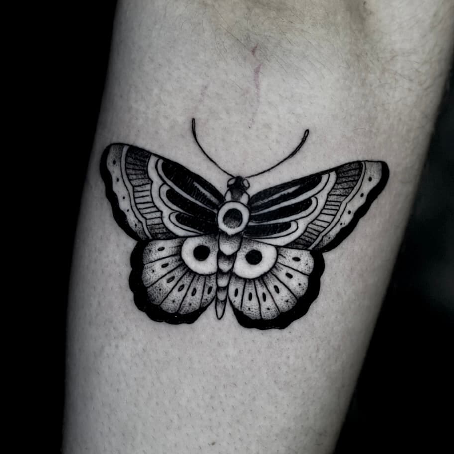 Zwart-wit traditionele vlinder tattoo op de onderarm.