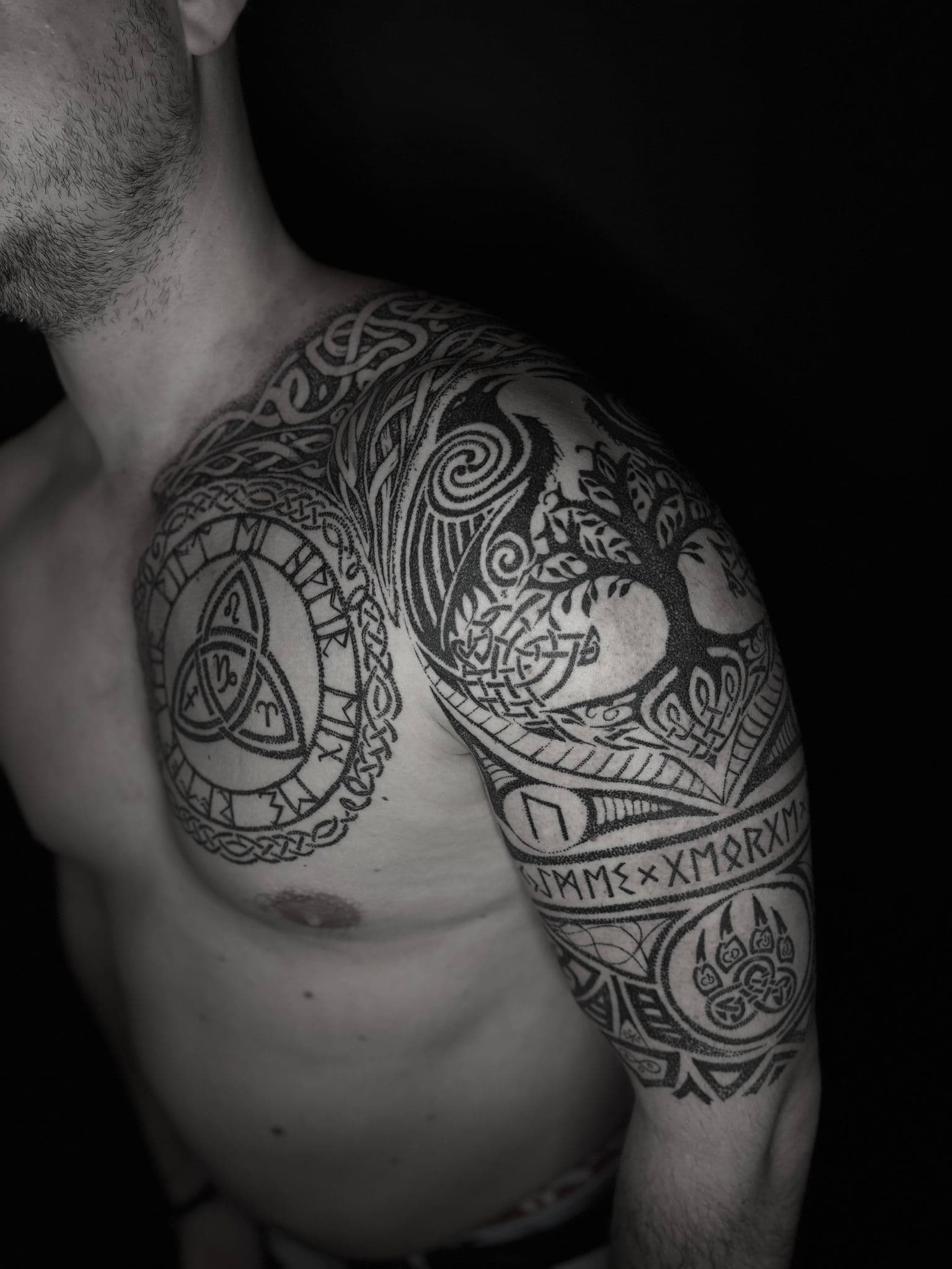 Grote Keltische tattoo met levensboom, runen en knoopwerk op schouder en borst.