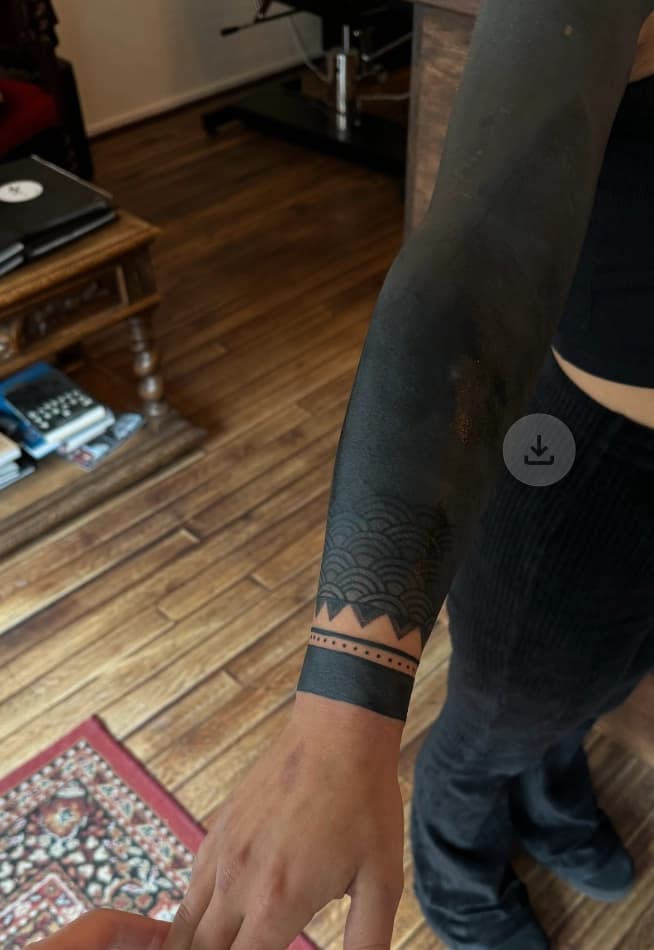 Blackout sleeve met geometrisch patroon op pols.