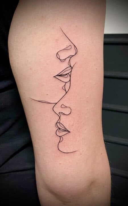 Fineline tattoo van twee gezichten in één lijn op de bovenarm.