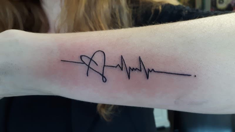 Minimalistische hartslag en hart tattoo op onderarm.