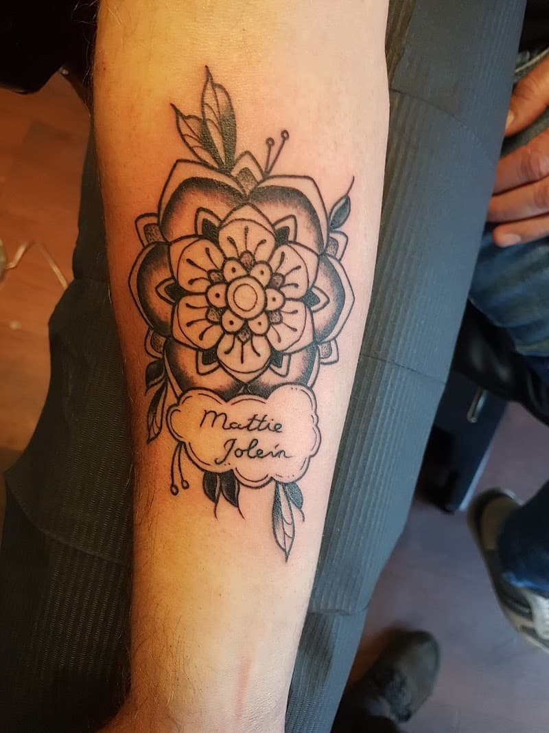 Blackwork mandala bloem met namen 'Mattie Jolein' in een wolkje op de onderarm.