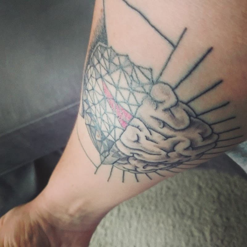 Illustratieve tattoo van een geometrisch hart en een realistisch brein op het onderbeen.