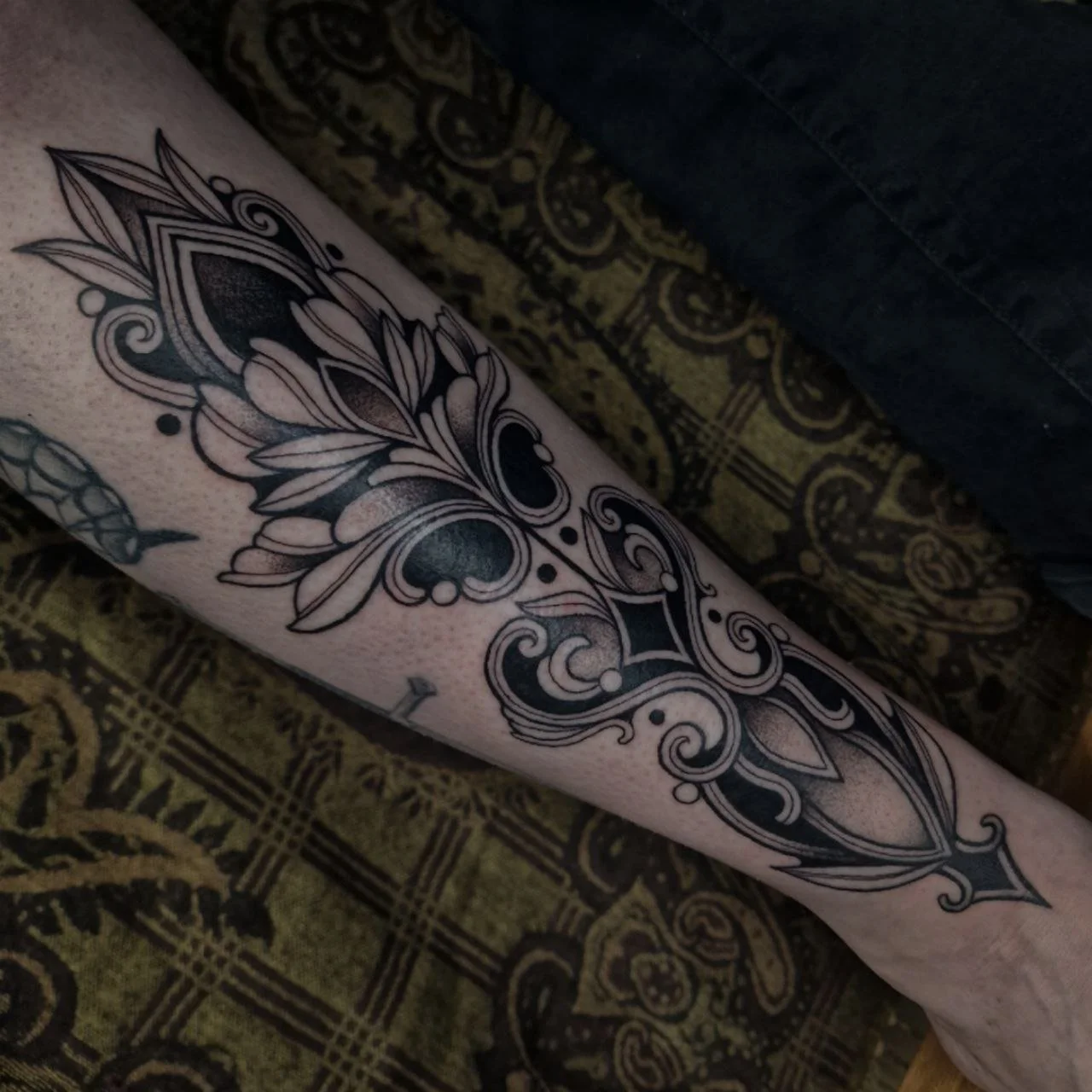 Grote ornamentele blackwork tattoo op het onderbeen.