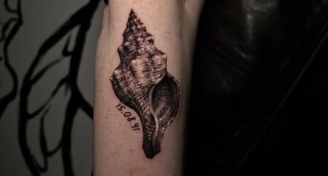 Realistische schelp met datum 15.08.41 op onderarm.