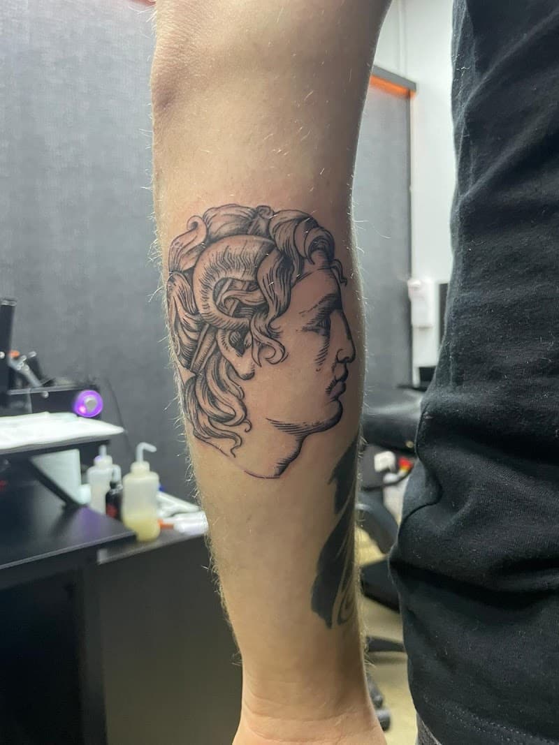 Zwart-wit gravure-stijl tattoo van een klassiek mannenhoofd met hoorns op de onderarm.