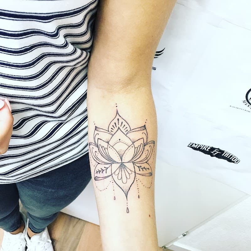 Fineline lotusbloem met dotwork details op de onderarm.