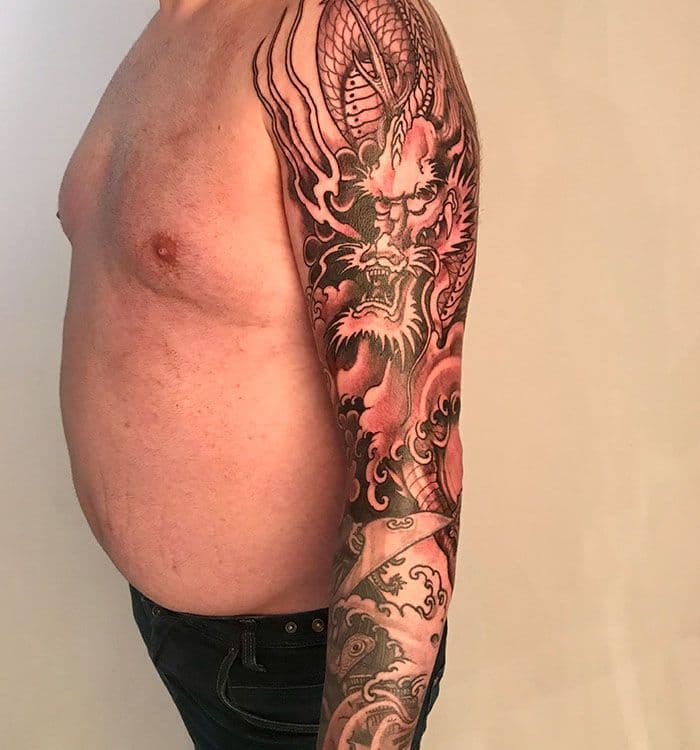 Grote Japanse draak tattoo op de volledige linkerarm.