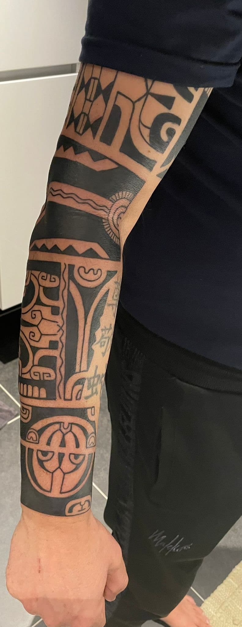Polynesische tribal half-sleeve tattoo op de onderarm en bovenarm.