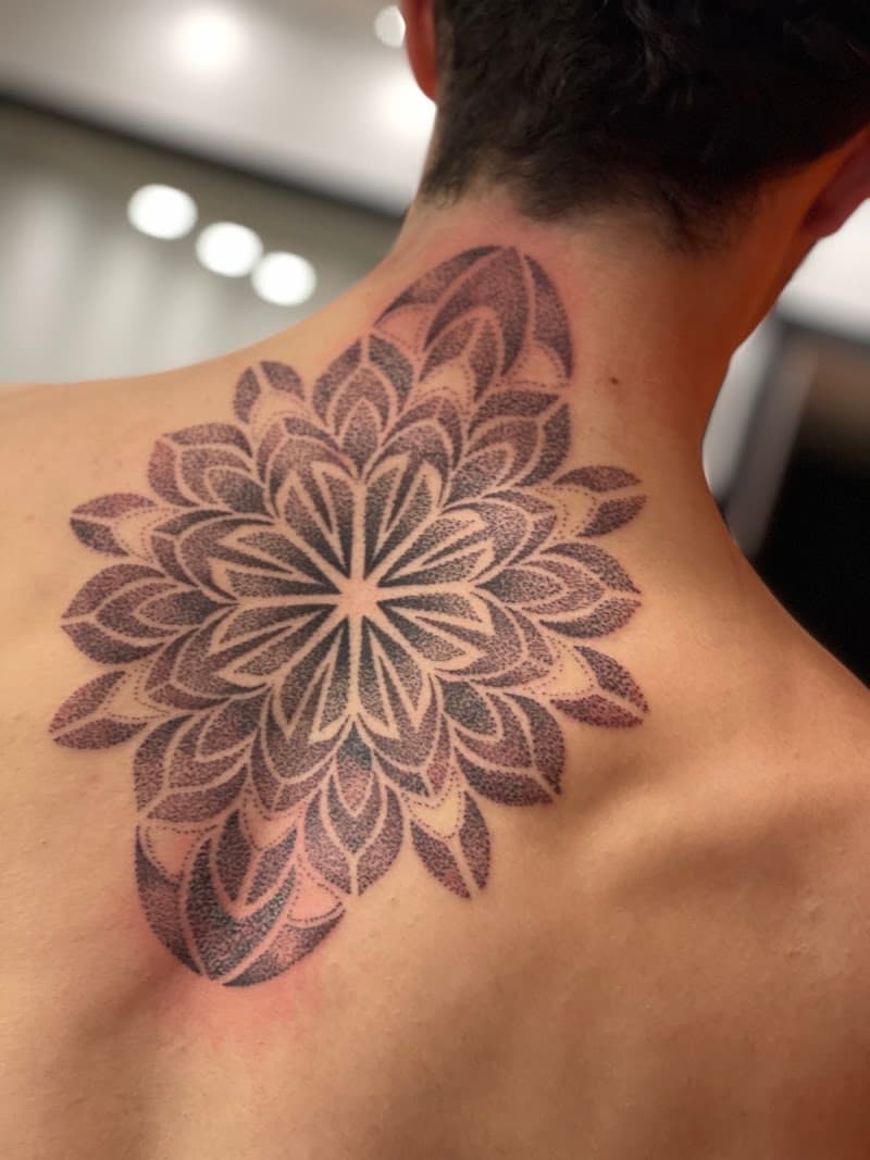 Dotwork mandala tattoo op de bovenrug en nek.