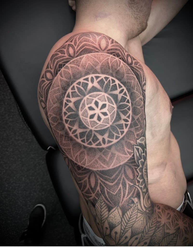 Grote dotwork mandala tattoo op bovenarm en schouder.