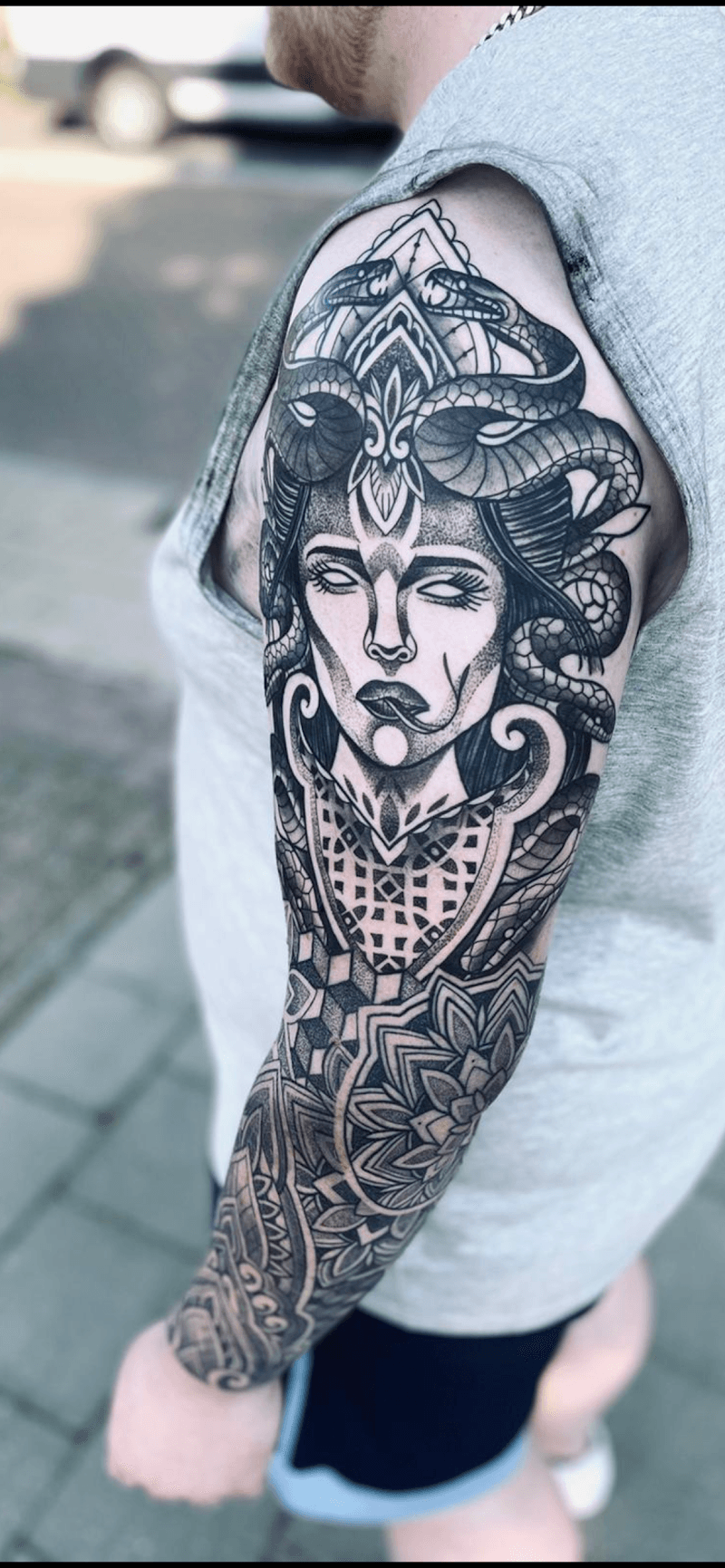 Blackwork Medusa en mandala sleeve tattoo op bovenarm.