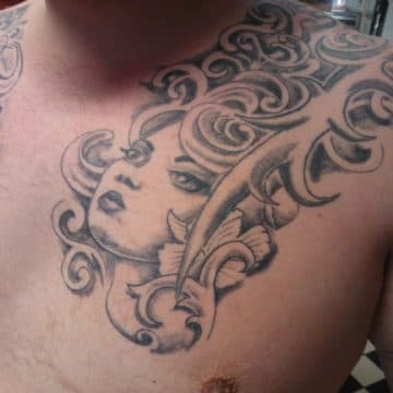 Zwart-wit tattoo van een vrouwenhoofd met krullend haar en bloem op de borst.