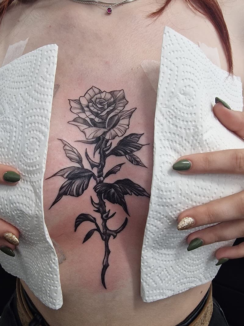 Zwart-wit roos met doornen op de borst.