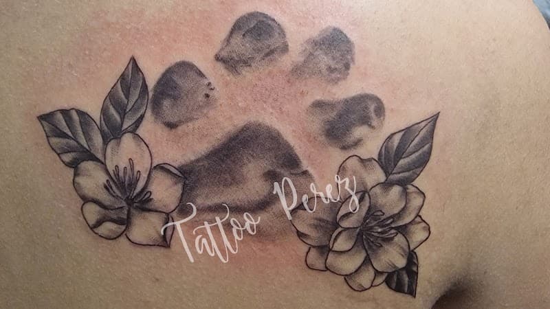 Hondenpootafdruk met bloemen en bladeren op schouderblad.