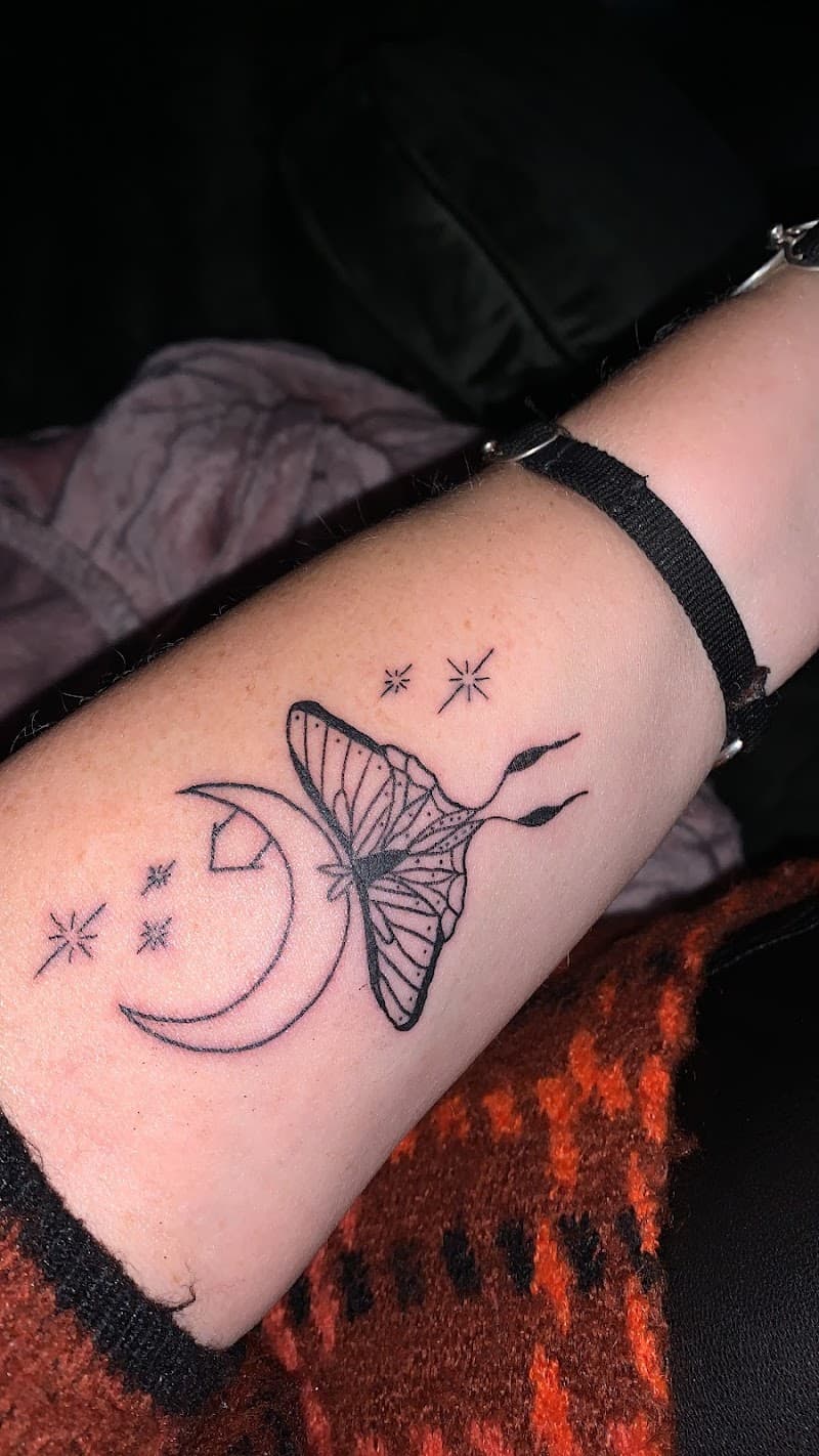 Fineline tattoo van een mot op een halve maan met sterren op de onderarm.