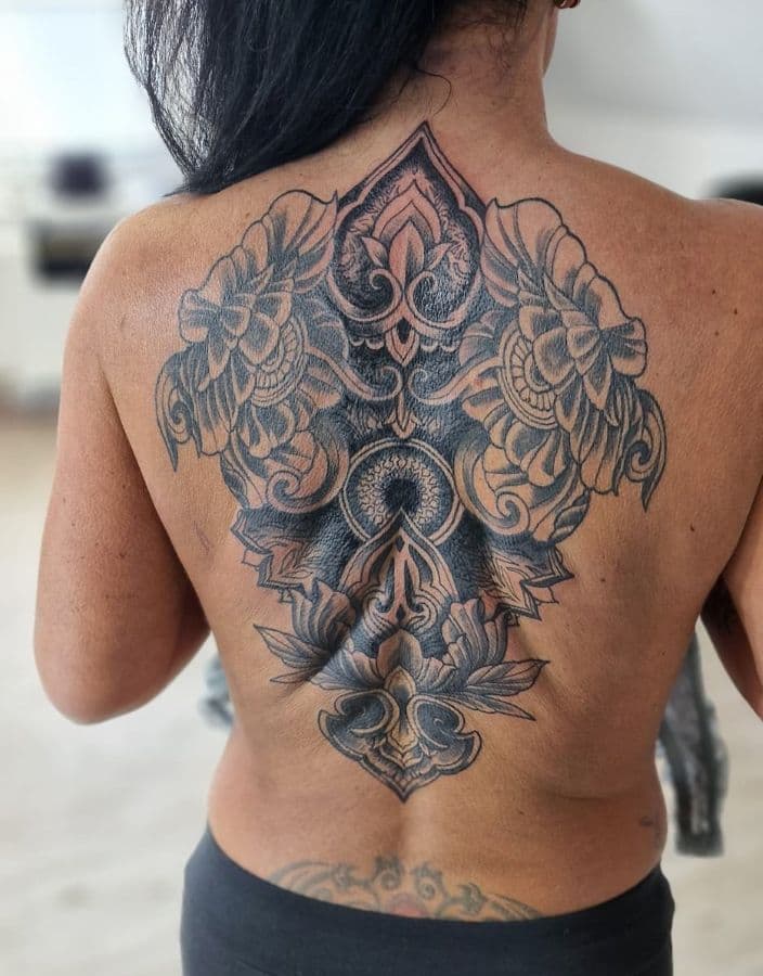 Grote, gedetailleerde mandala en bloemen tattoo op de rug.