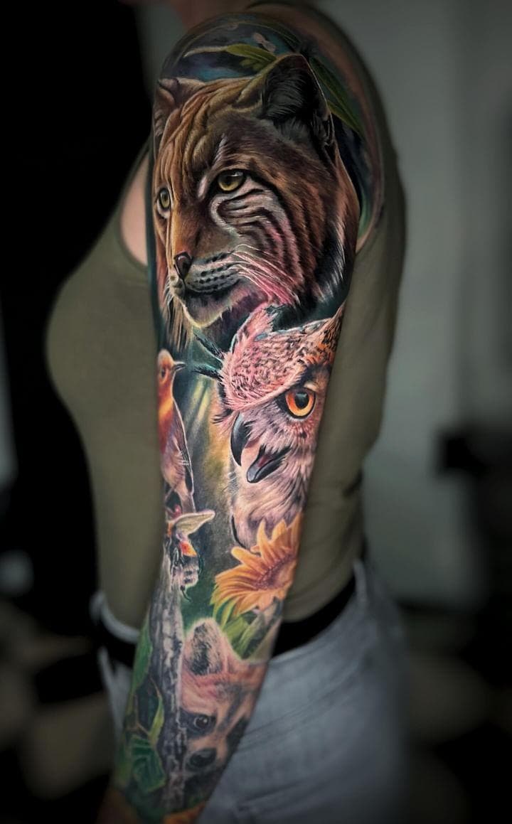 Realistische sleeve tattoo met lynx, uil, vogel en zonnebloem.