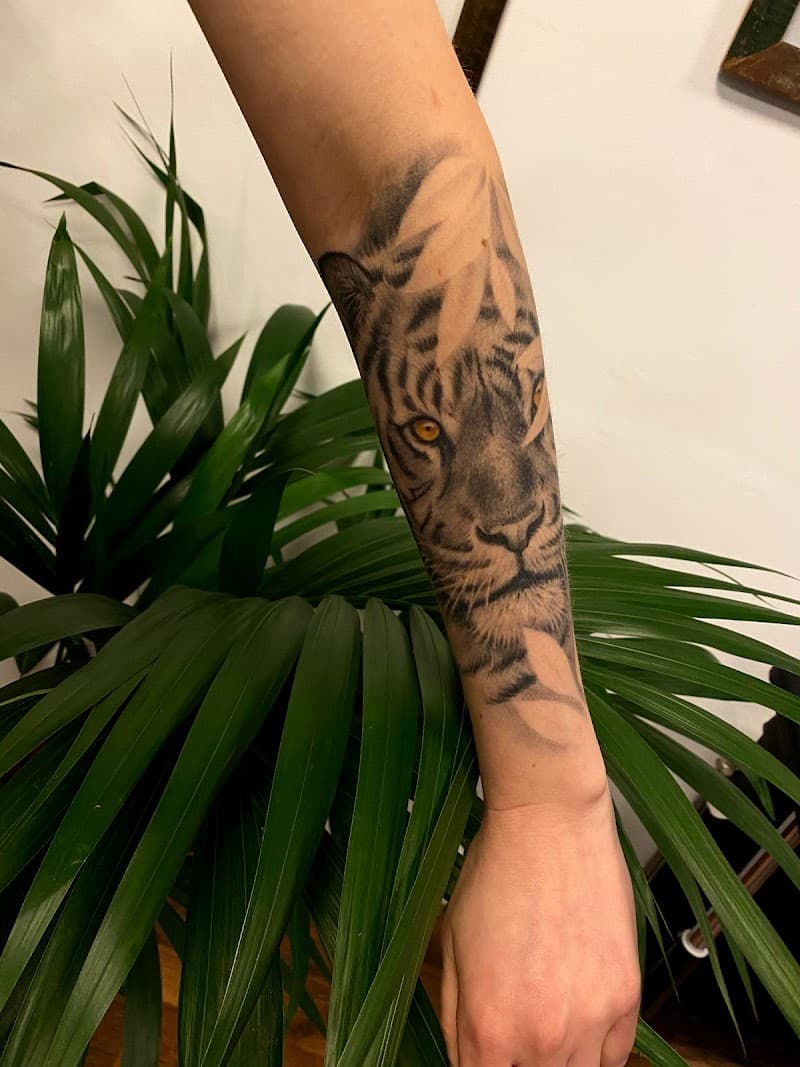 Realistische tijgerkop met bladeren op onderarm